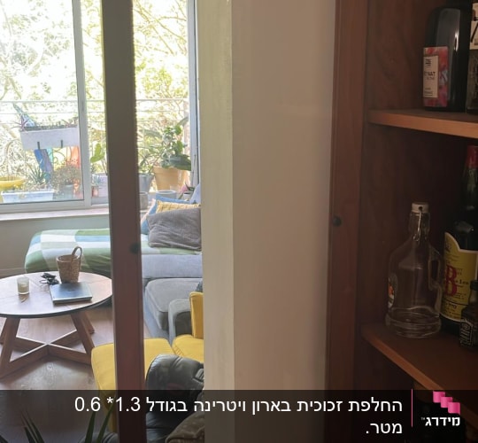 דלת זכוכית פתוחה בארון עץ עם בקבוקים